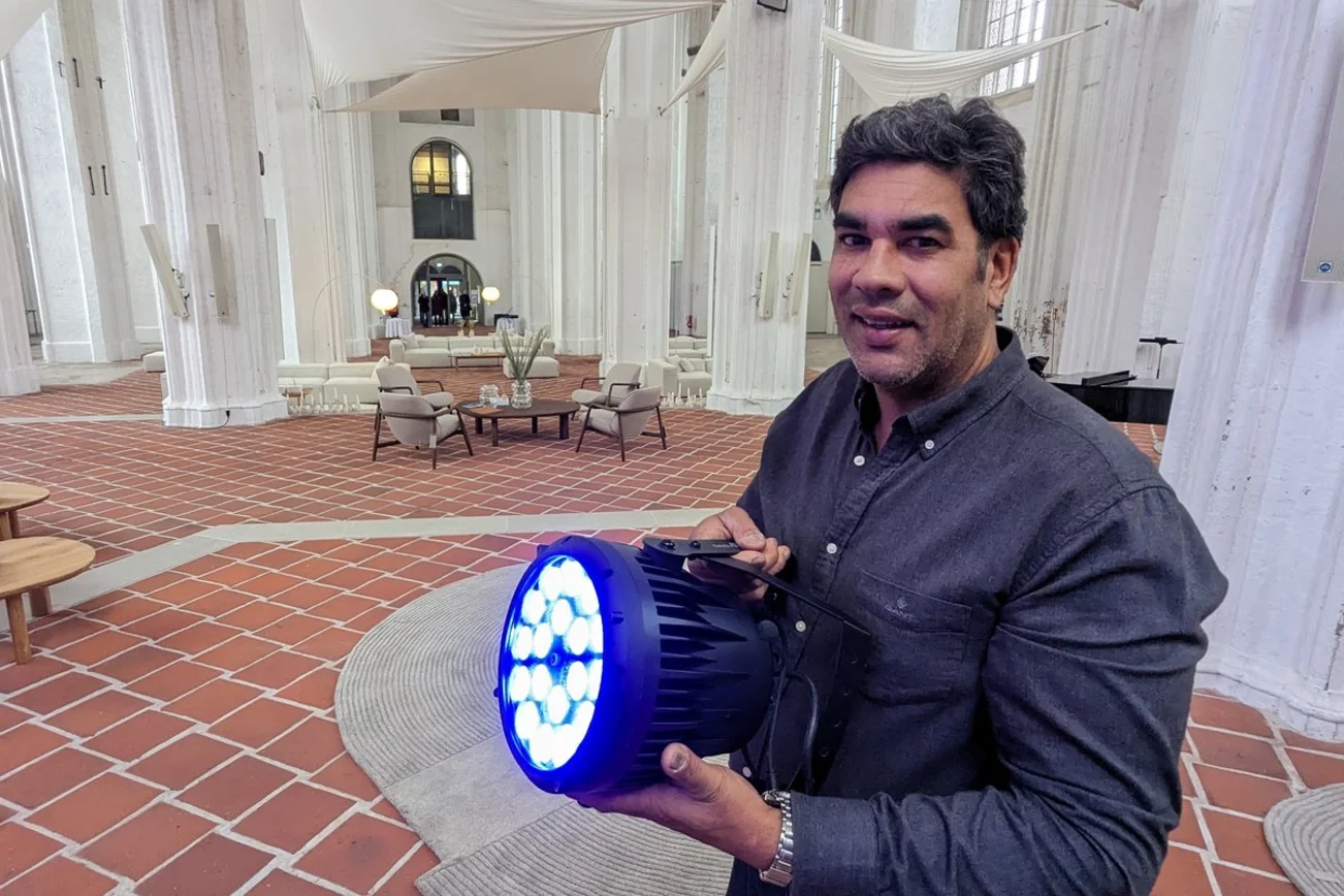 Ein Mann steht in einer Kirche und hält einen blau leuchtenden Scheinwerfer.