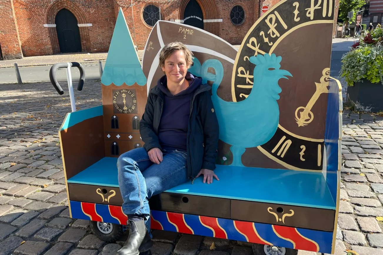 Pastorin Reichelt sitzt auf der bunt bemalten Bank und lächelt in die Kamera.