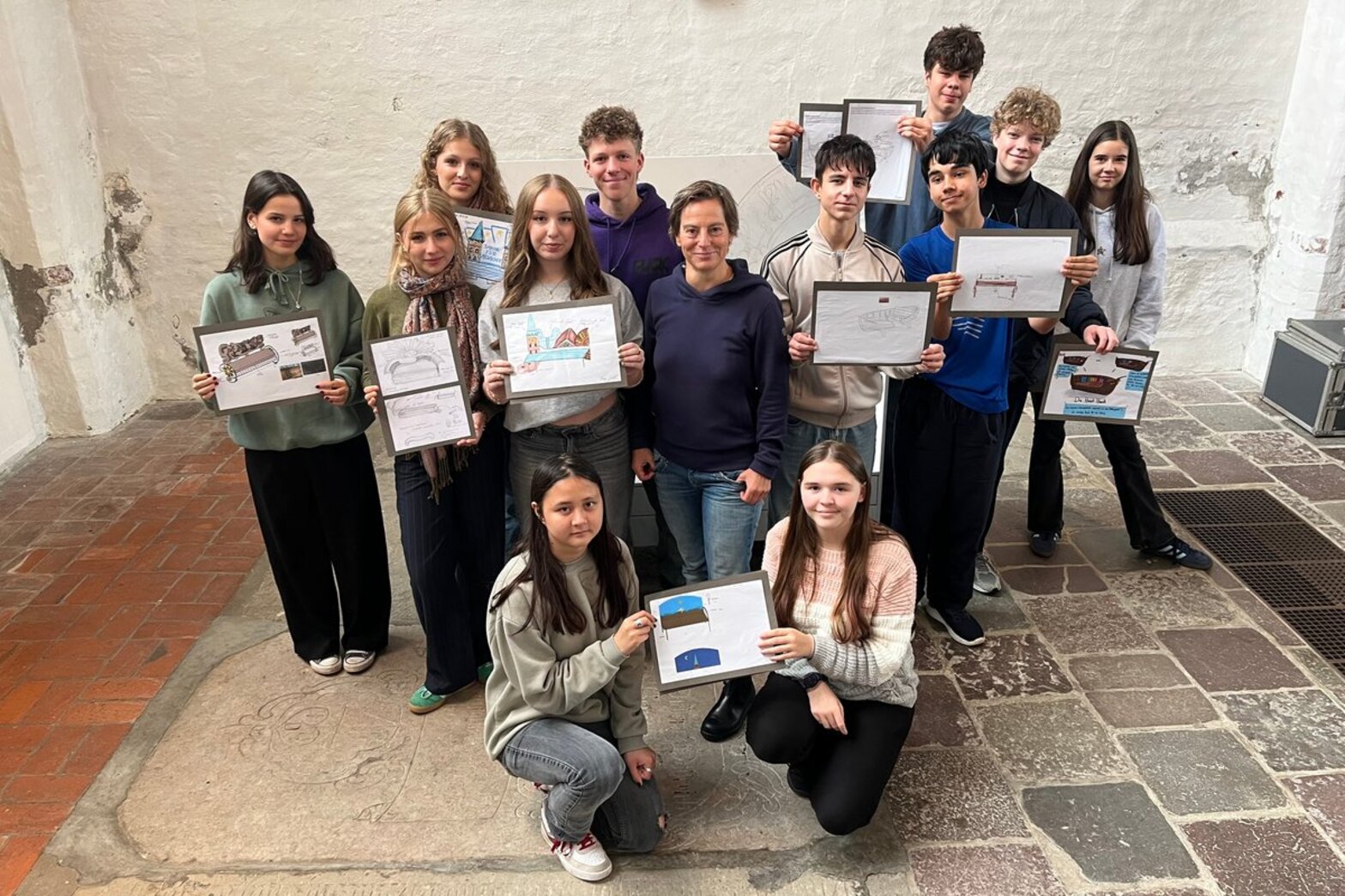 Einige Schüler und Schülerinnen präsentieren ihre Entwürfe in die Kamera.