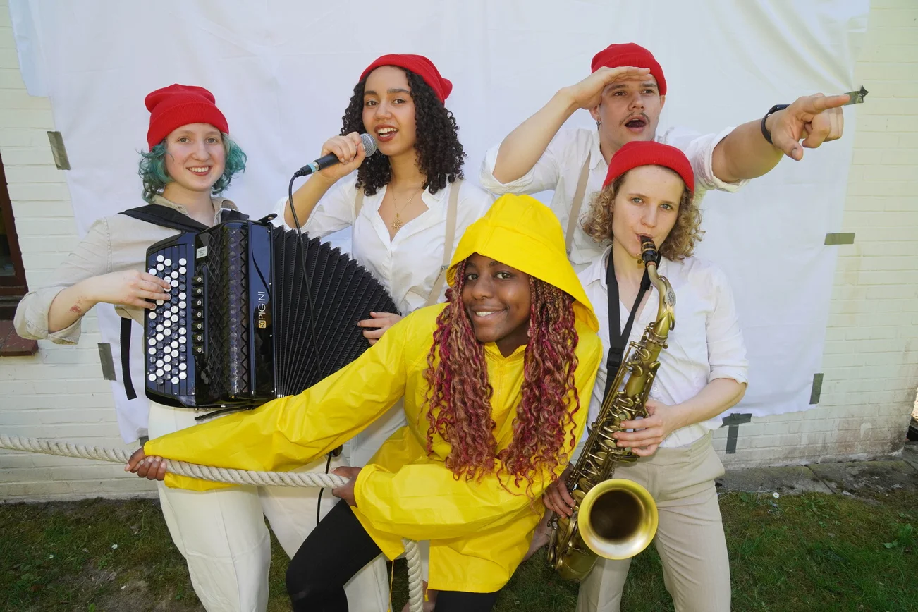Darsteller eines Musicals mit Akkordeon, Saxofon und einer Person im Friesennerz.