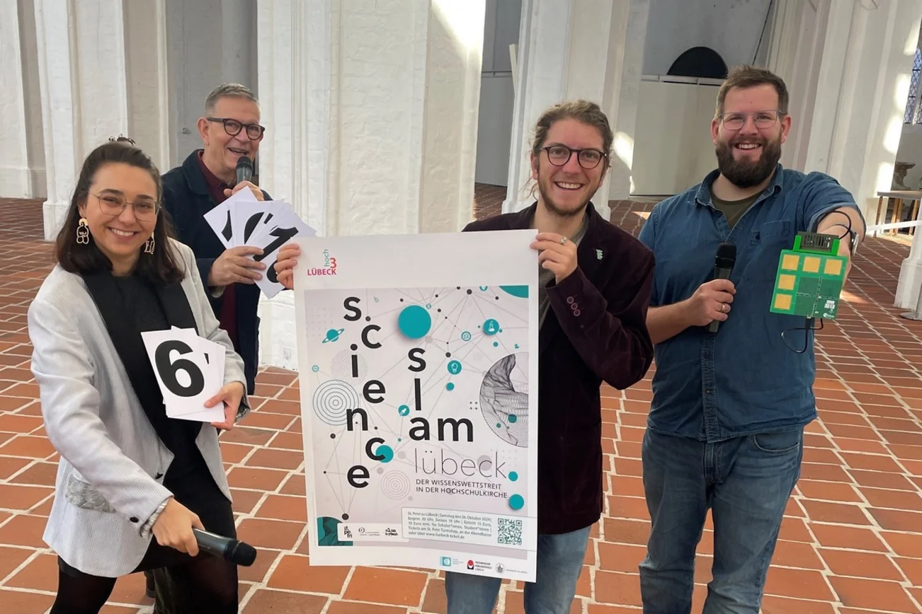 Vier Menschan halten in der St.-Petri-Kirche das Science-Slam-Plakat hoch.