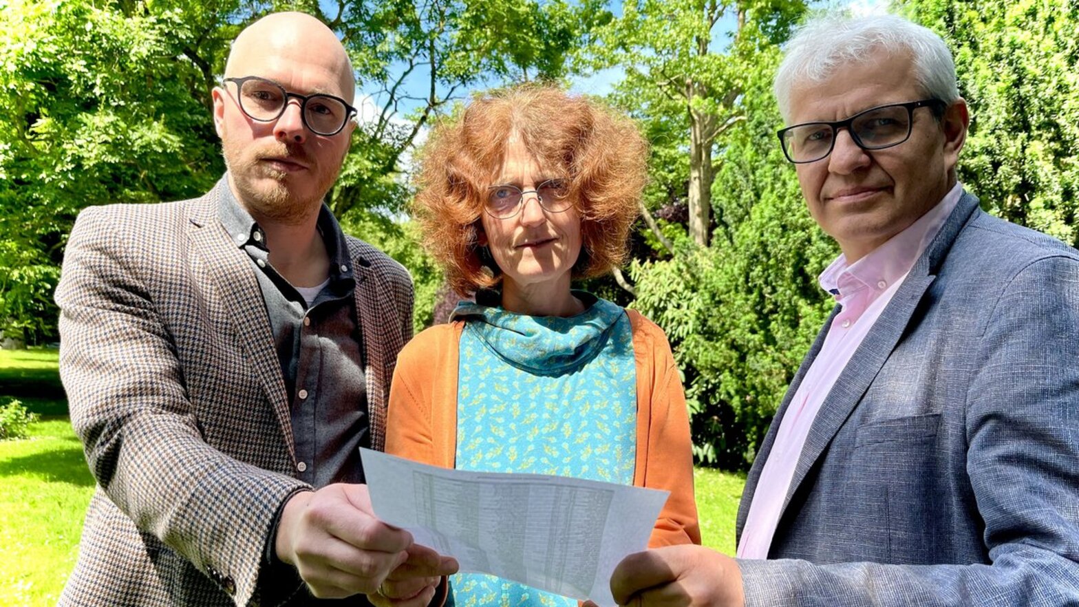 Drei Menschen halten einen Brief in den Händen