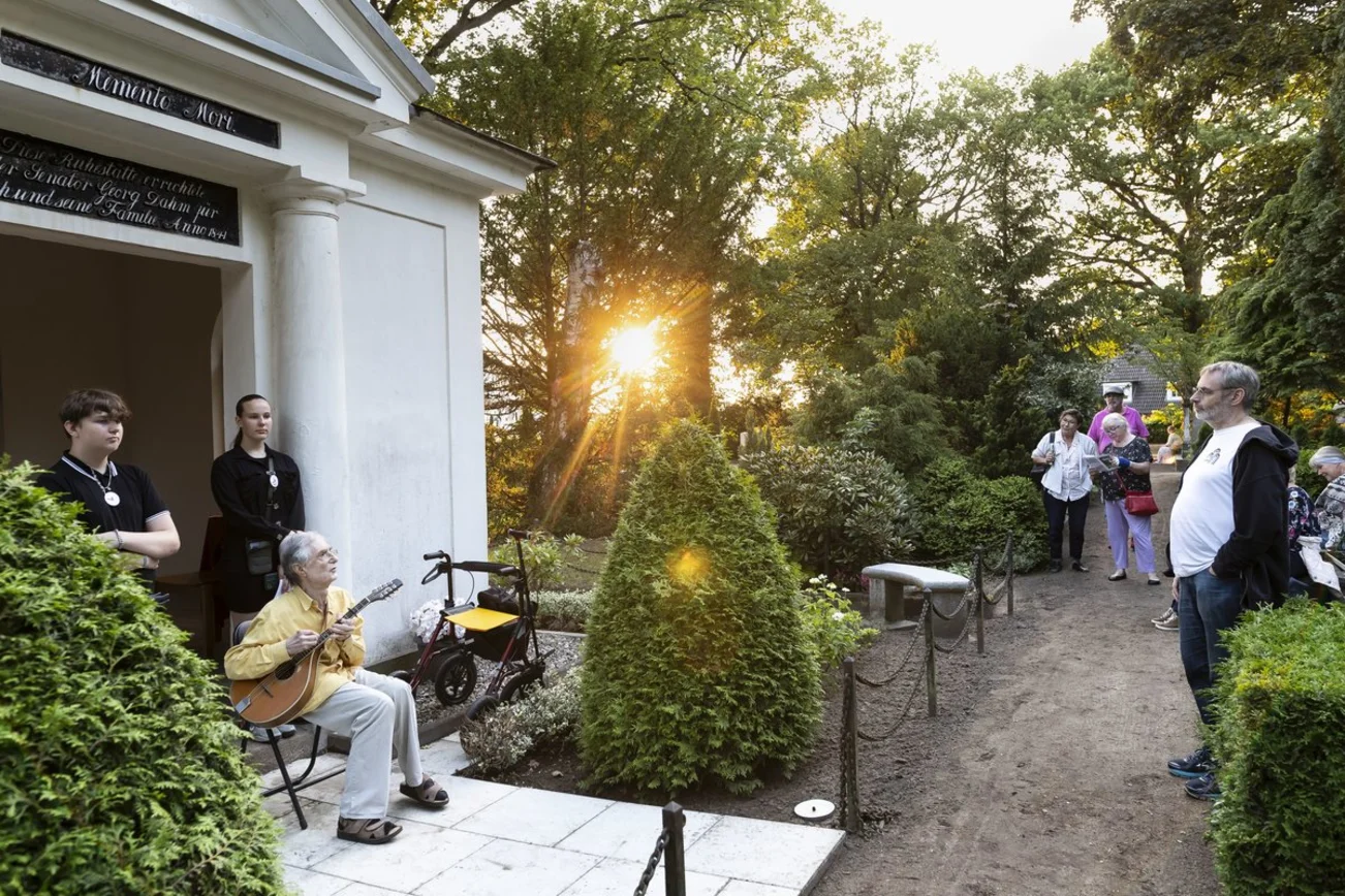 Ein Mann spielt vor einem Mausoleum auf einer Mandola
