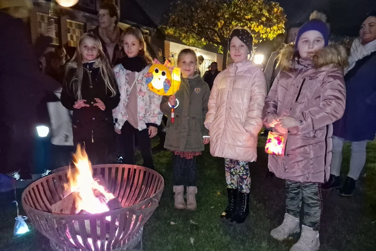Kinder mit Laternen vor einem Feuerkorb