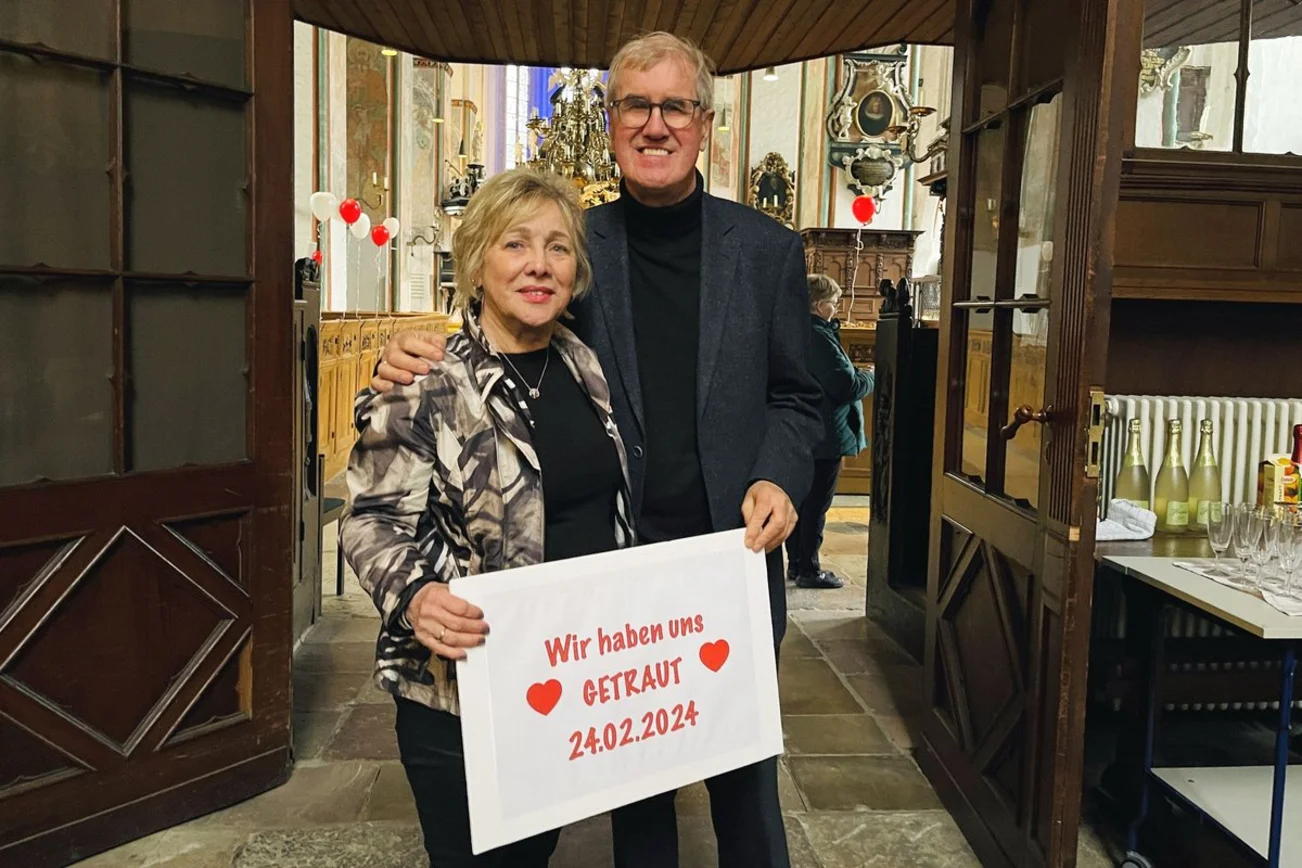 Ein Paar steht in einer Kirche und hält ein Schild in der Hand.