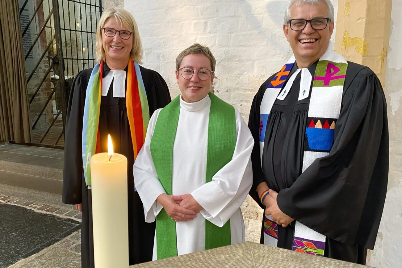 Zwei Frauen und ein Mann stehen in einer Kirche.