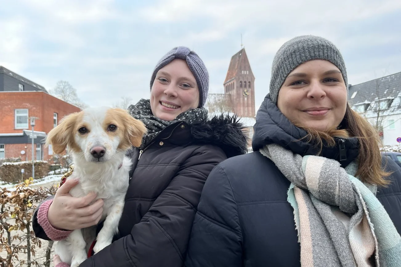 Zwei Frauen und ein Hund vor einer Kirche
