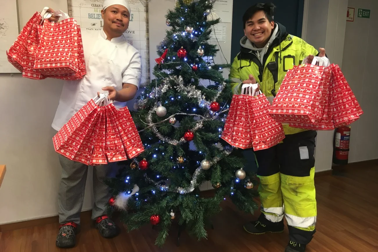 Zwei Menschen mit Geschenktüten an einem Baum.