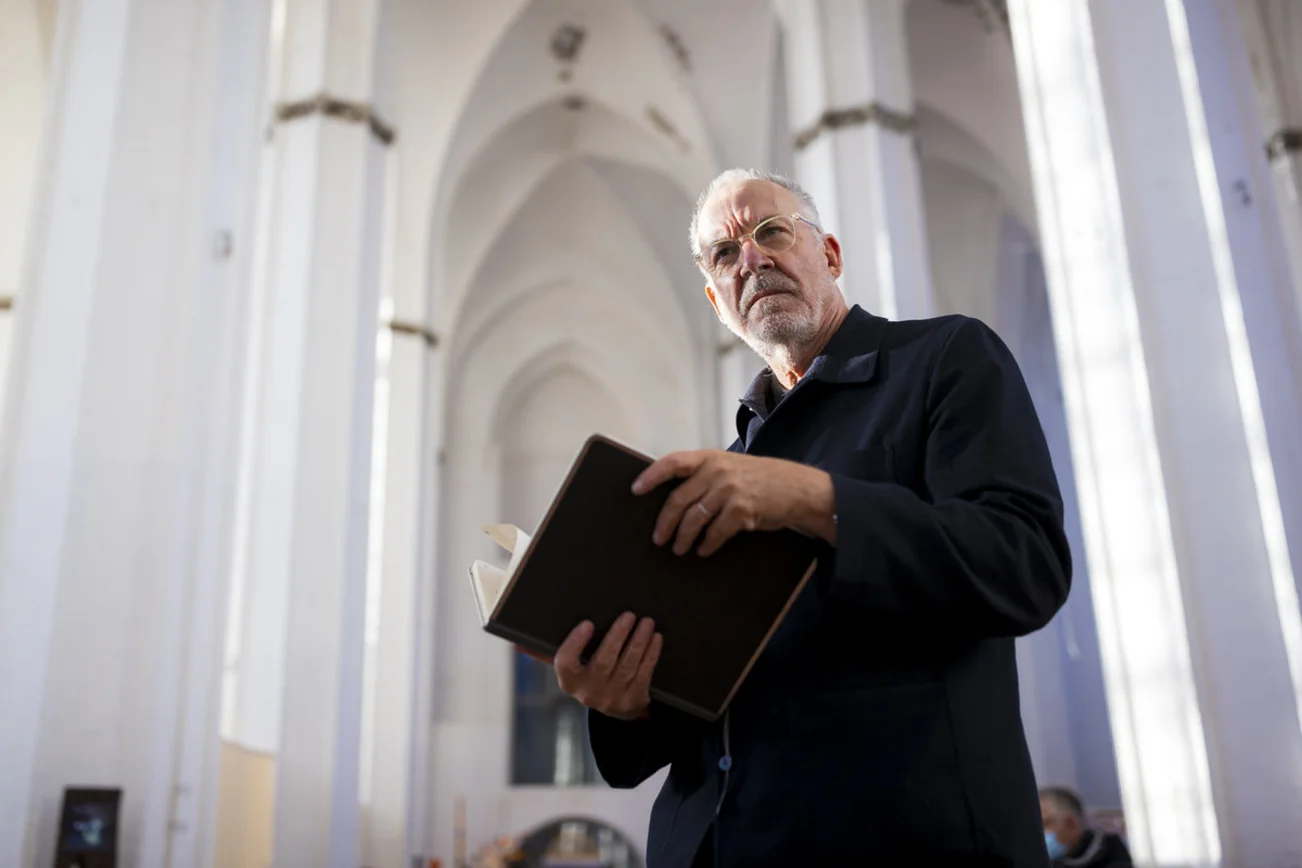 Ein Mann steht in einer Kirche und hält ein Buch in den Händen.