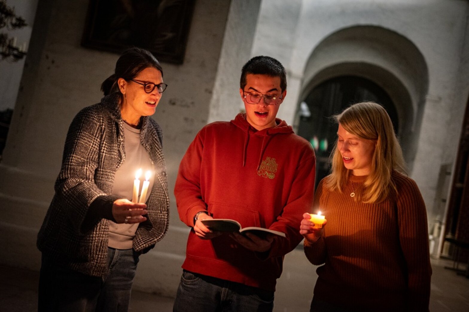 Drei Menschen singen in einer Kirche