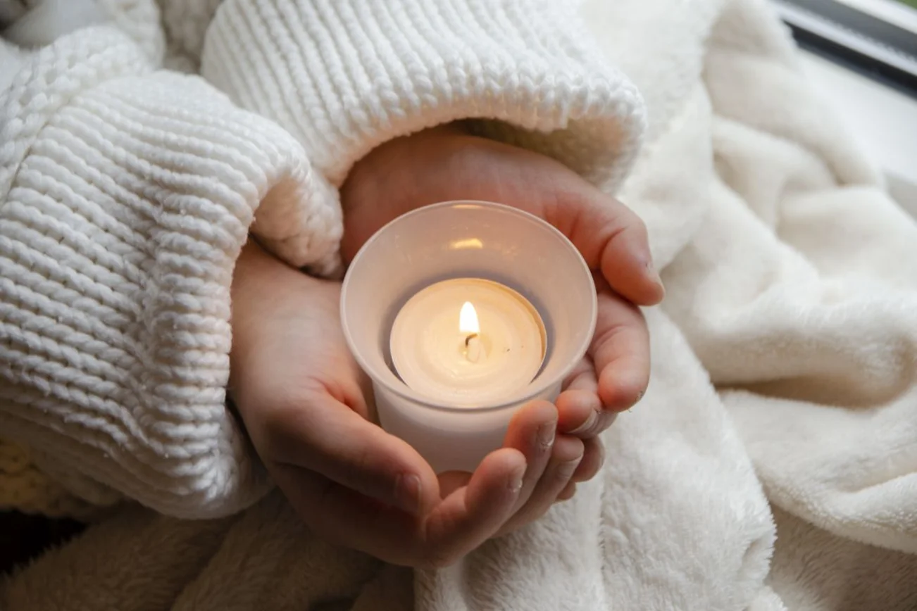 Kleine Hände tragen ein Teelicht in den Händen
