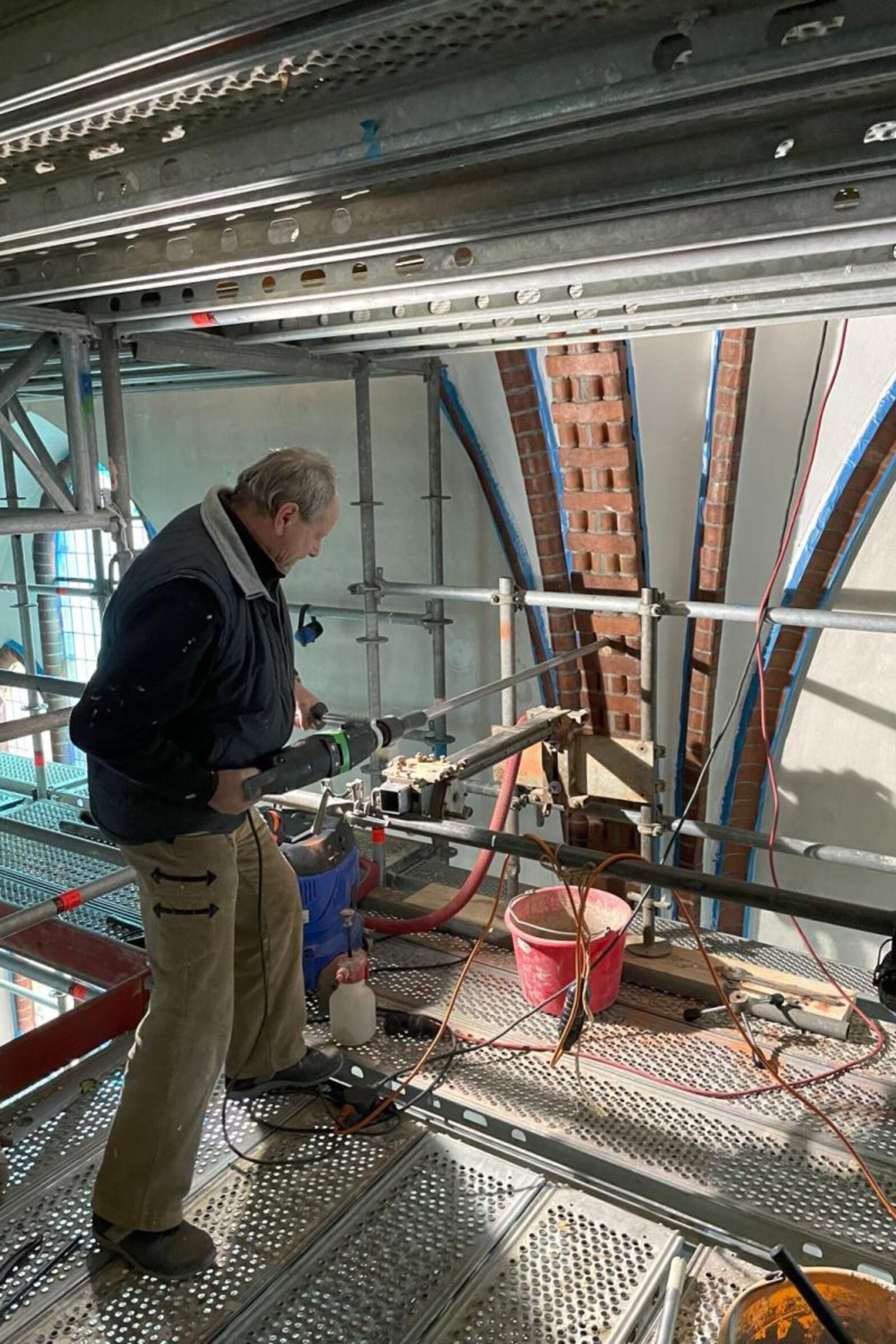 Mannsteht auf Gerüst und bohrt