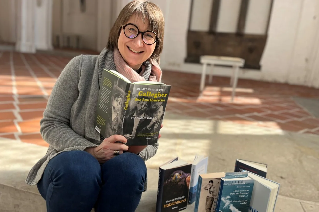 Eine Frau sitzt auf einer Treppe in einer Kirche mit einem Buch in der Hand