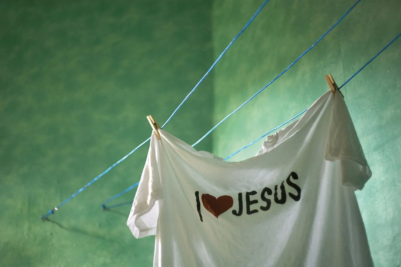 Ein weißes T-Shirt hängt auf der Wäscheleine in einem grünen Raum