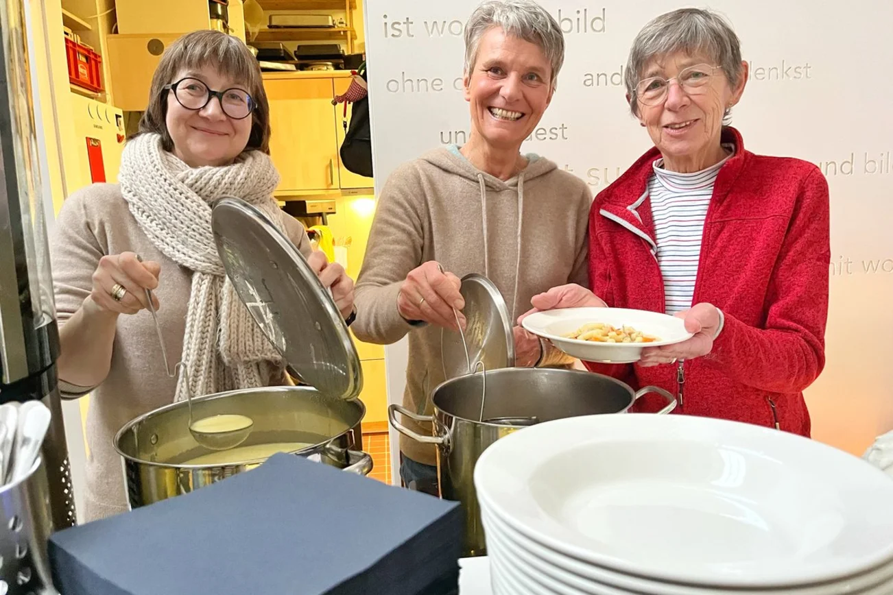 Drei Personen schenken Suppe aus. 