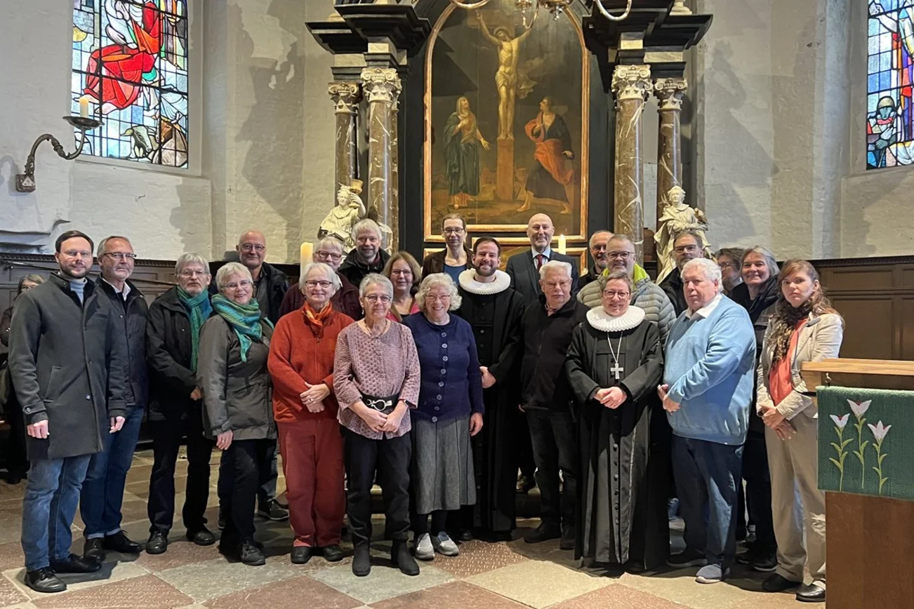 Eine Gruppe Menschen steht in einer Kirche vor dem Altarbild.