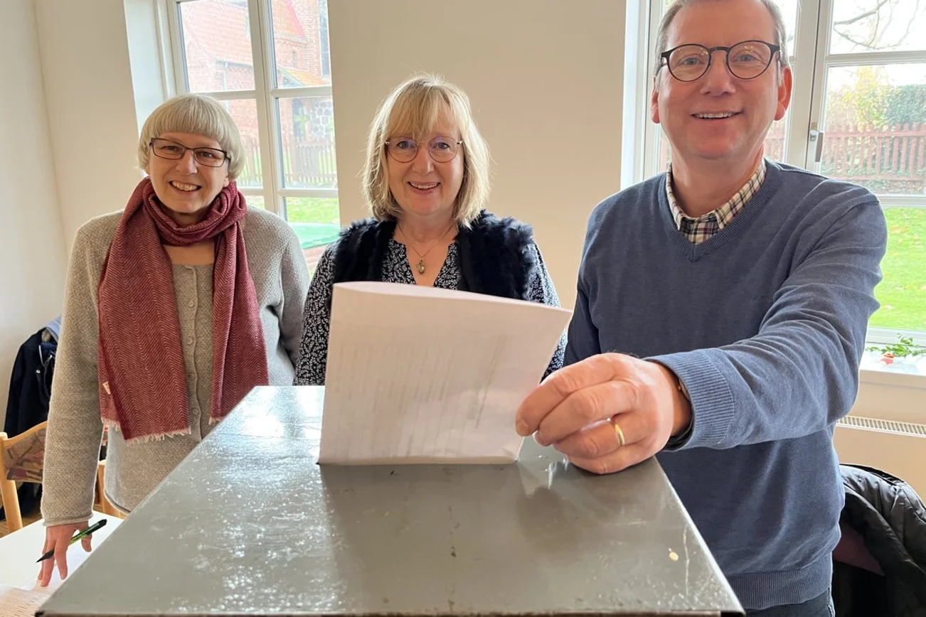 Drei Personen an einer Wahlurne