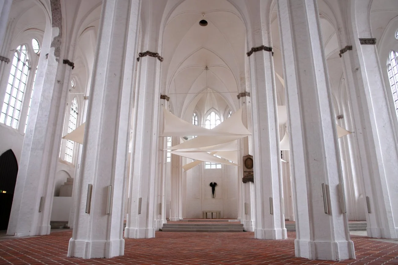 Mehrere weiße Säulen in einer Kirche mit weißen Segeln