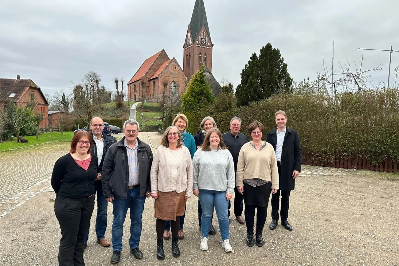 Mehrere Personen im Vordergrund, im Hintergrund Kirche