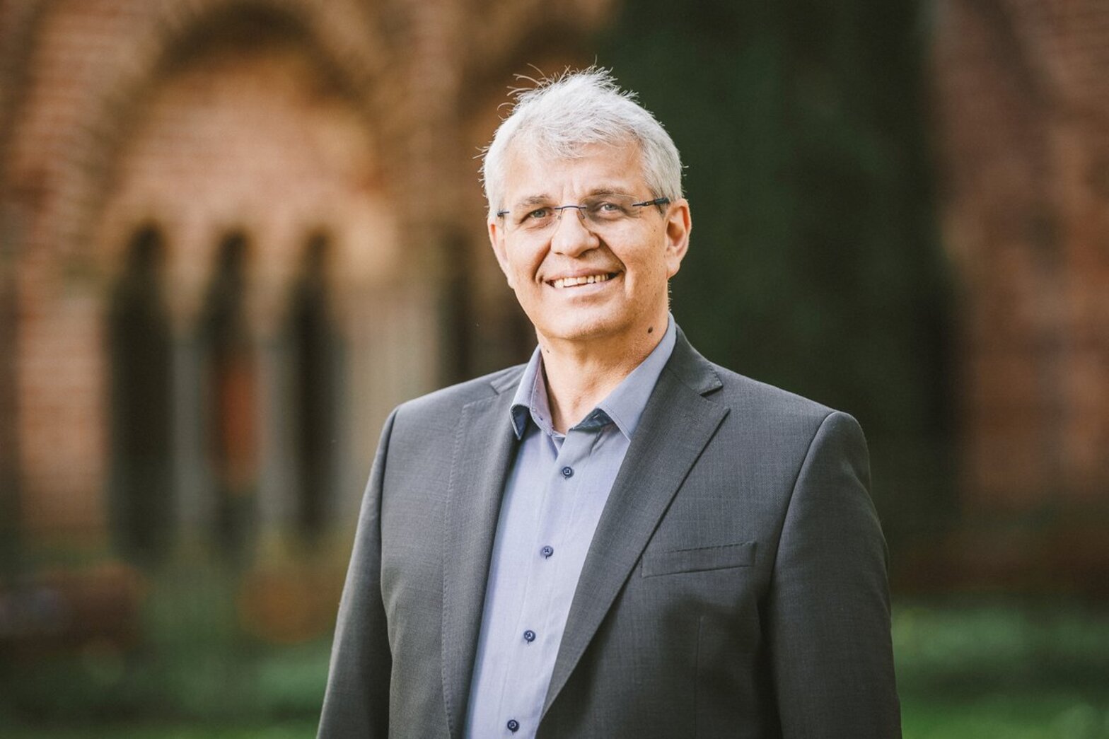 Ein Mann mit grauem Sakko lächelt in die Kamera.