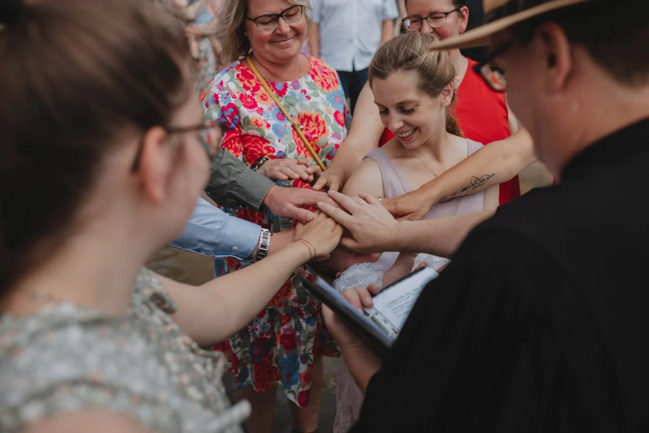 Erwachsene und Kinder halten ihre Hände über den Kopf eines Säuglings