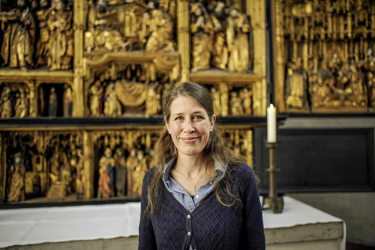 Eine Frau steht lächelnd in einer Kirche