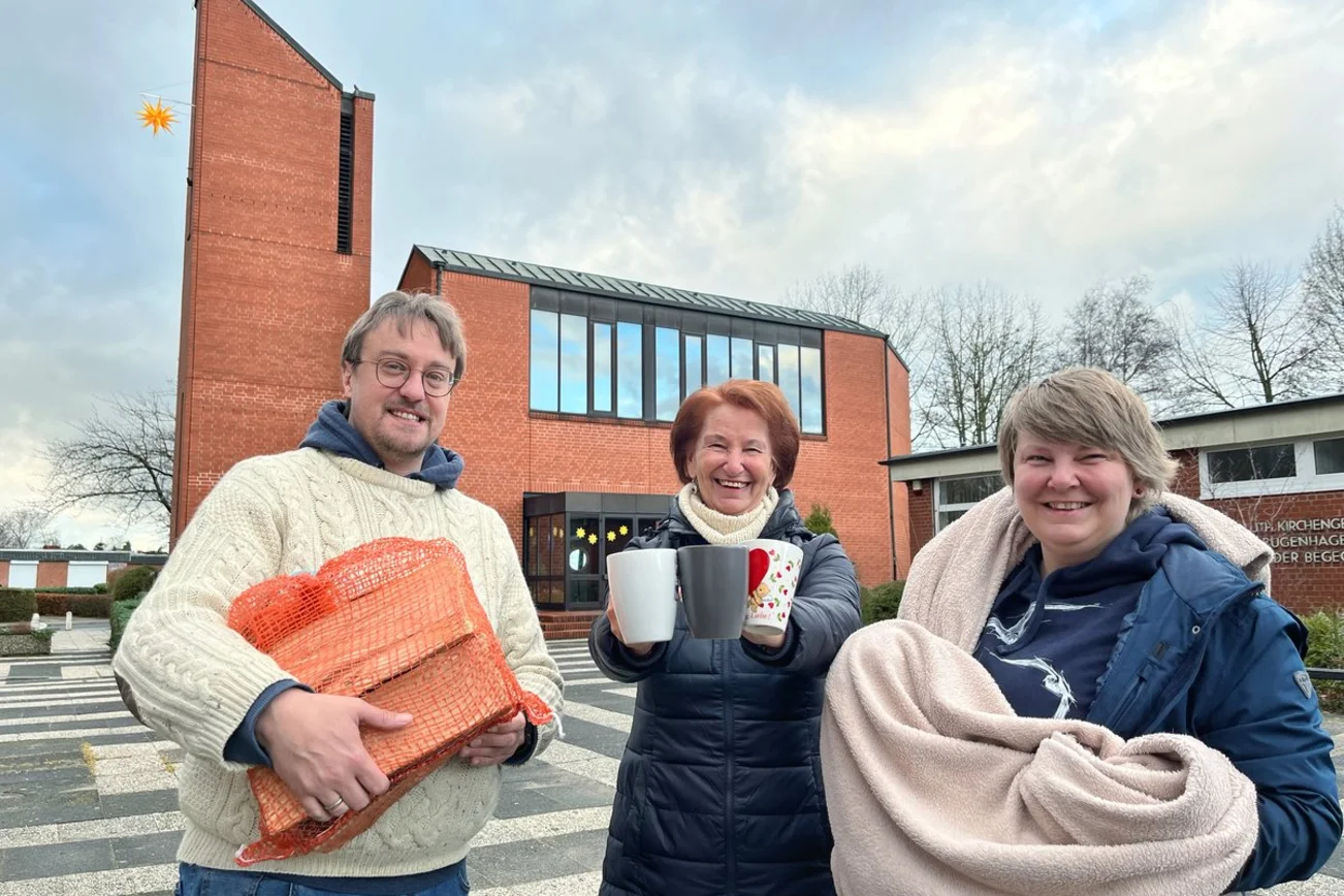 Drei Personen stehen vor einer Kirche. 