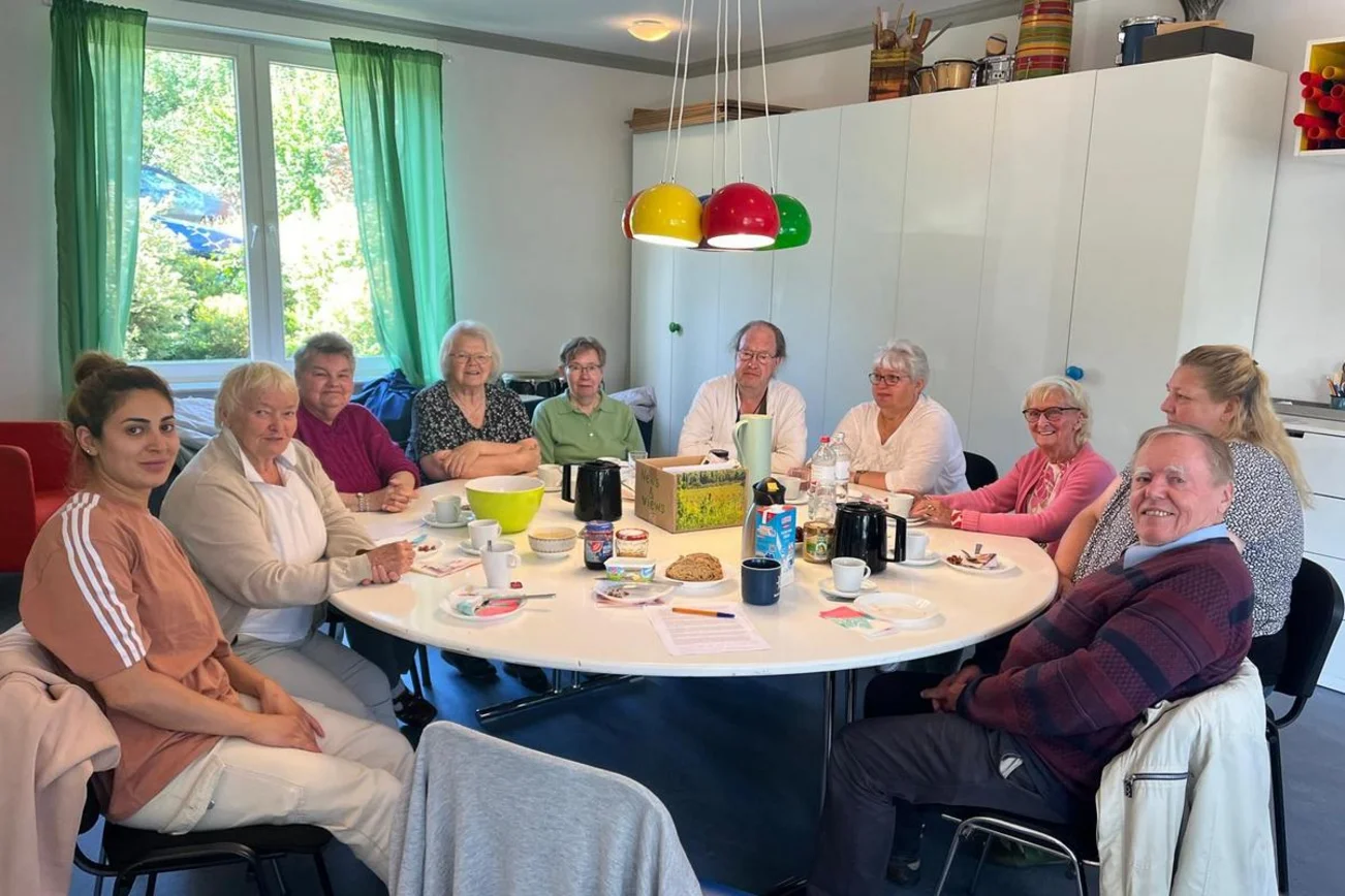 Viele Menschen sitzen an einem runden Tisch.