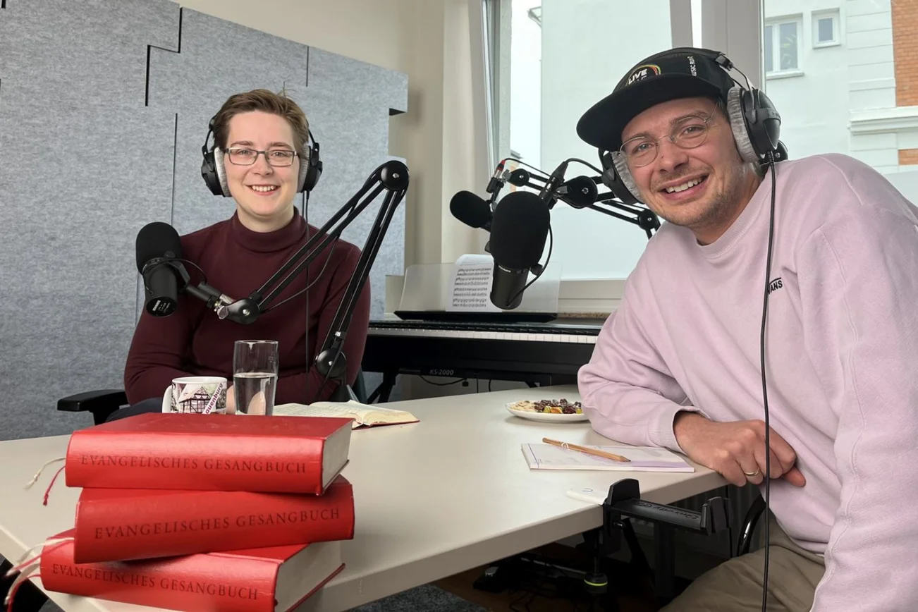 Zwei Personen sitzen an einem Tisch mit Mikrofonen.