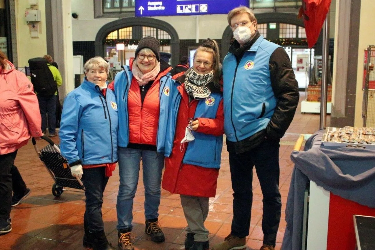 Vier Personen mit Westen der Bahnhofsmission lächeln in die Kamera