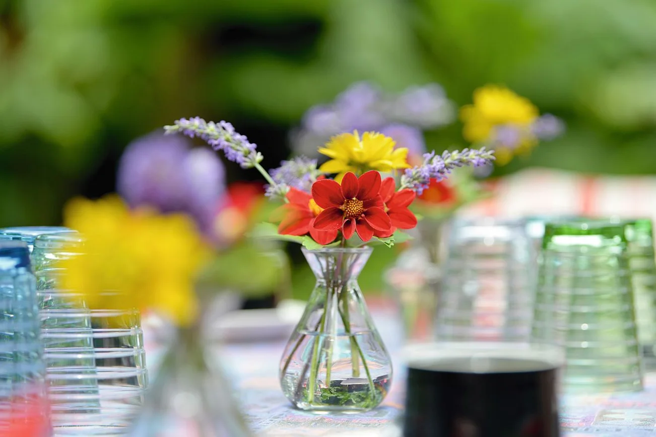 Viele Gläser stehen auf einem Tisch mit weißer Tischdecke und in der Mitte ist ein Blumenstrauß
