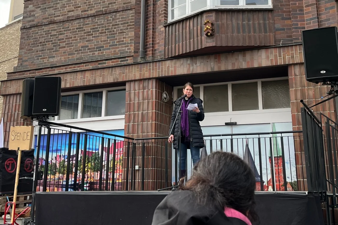 Eine Frau steht auf einem Podium und hät eine Rede.