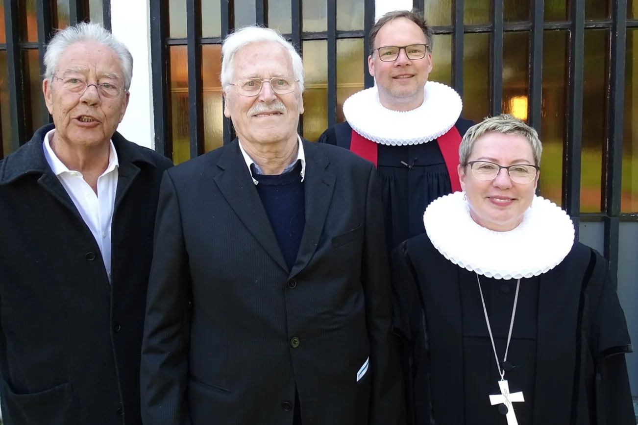 Vier Personen stehen vor einer Kirche. 