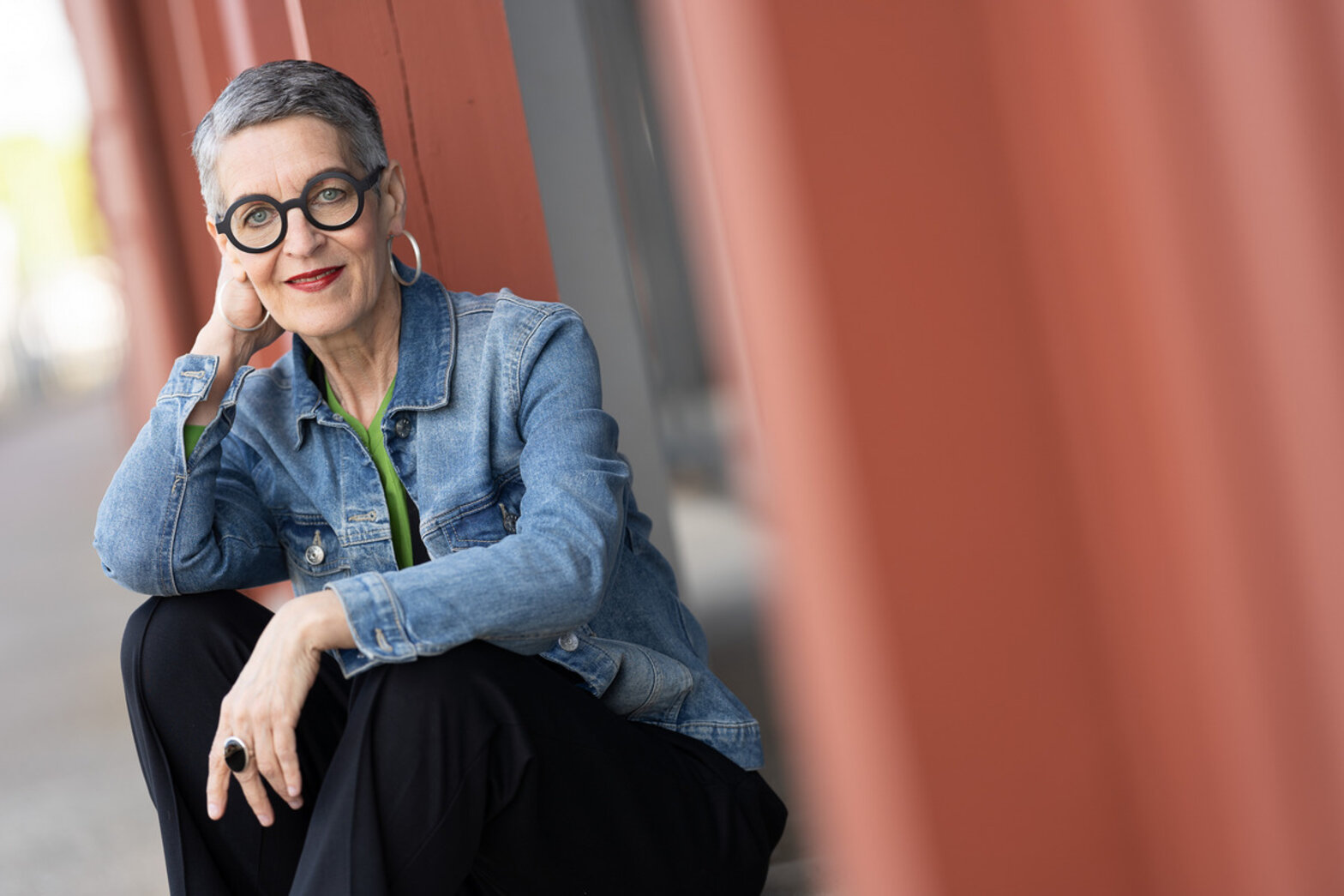 Frau lächelt lässig hockend in die Kamera.