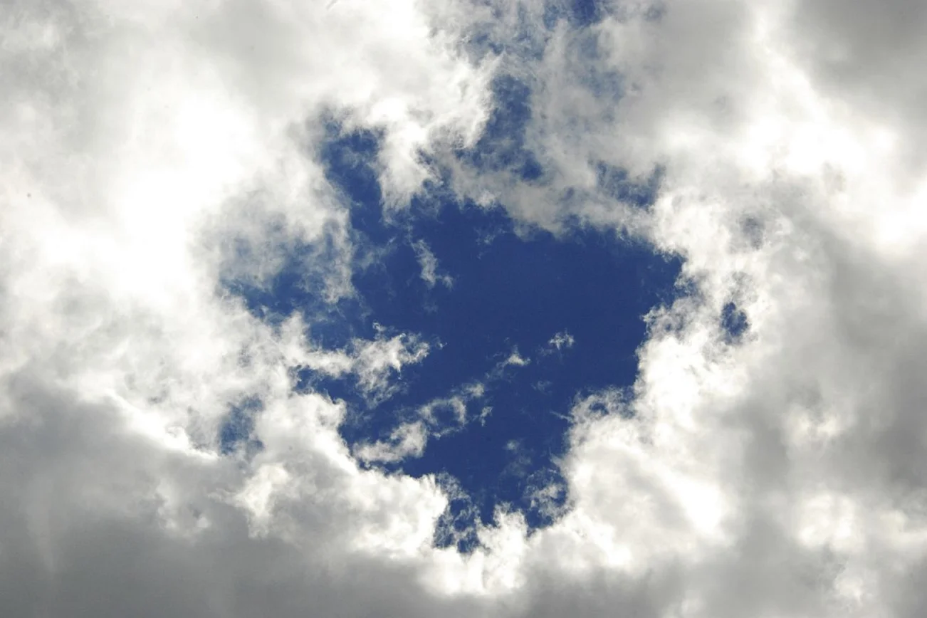 Ein Kreis blauer Himmel leuchtet durch eine Wolkendecke
