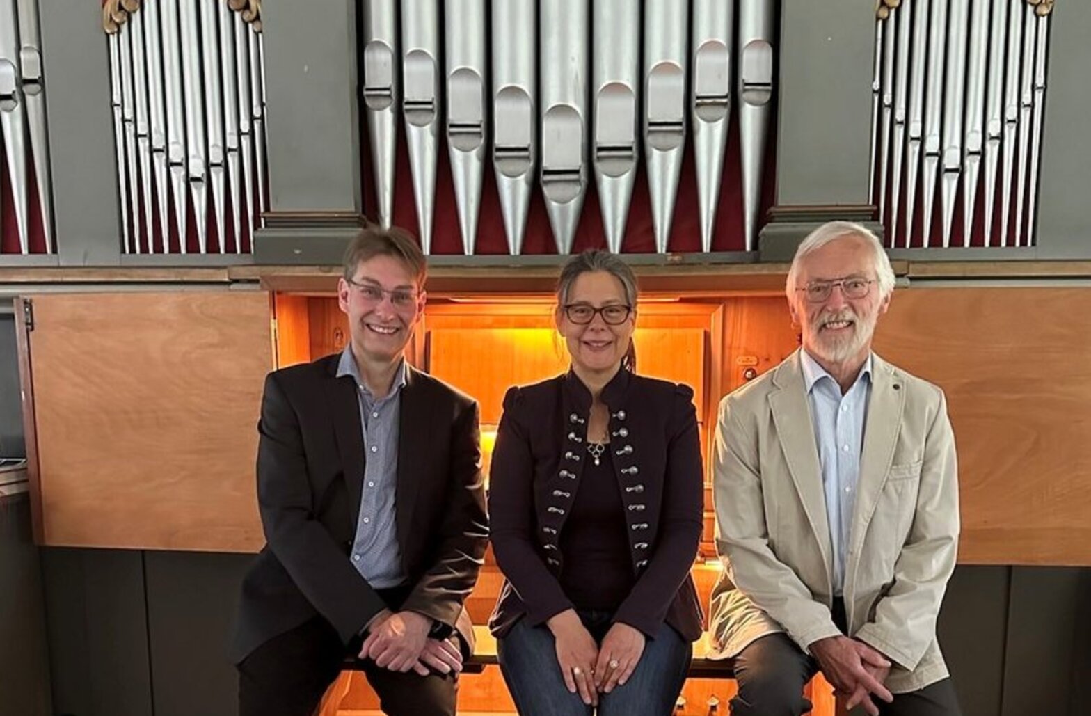 Drei Personen vor einer Orgel