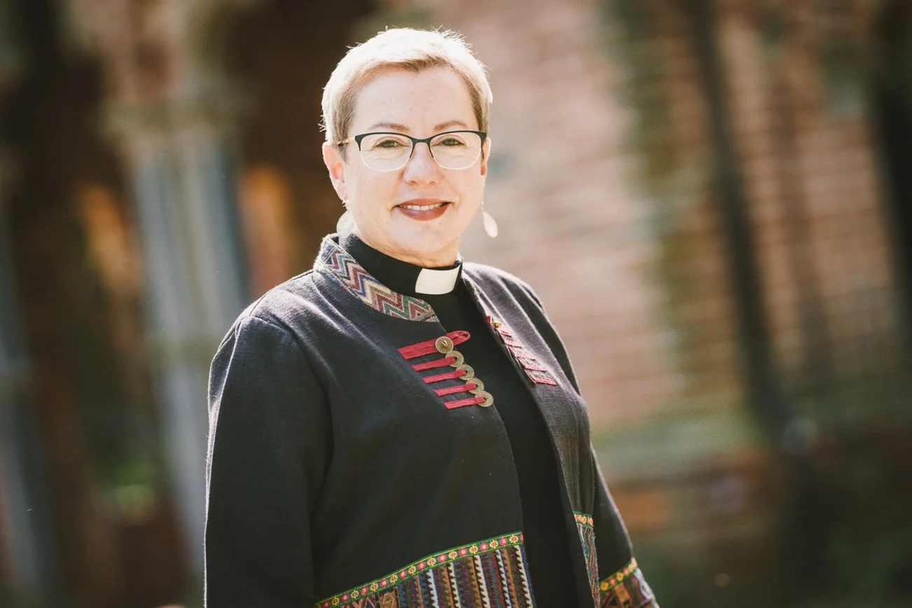 Eine Frau mit kurzen Haaren lächelt in die Kamera.