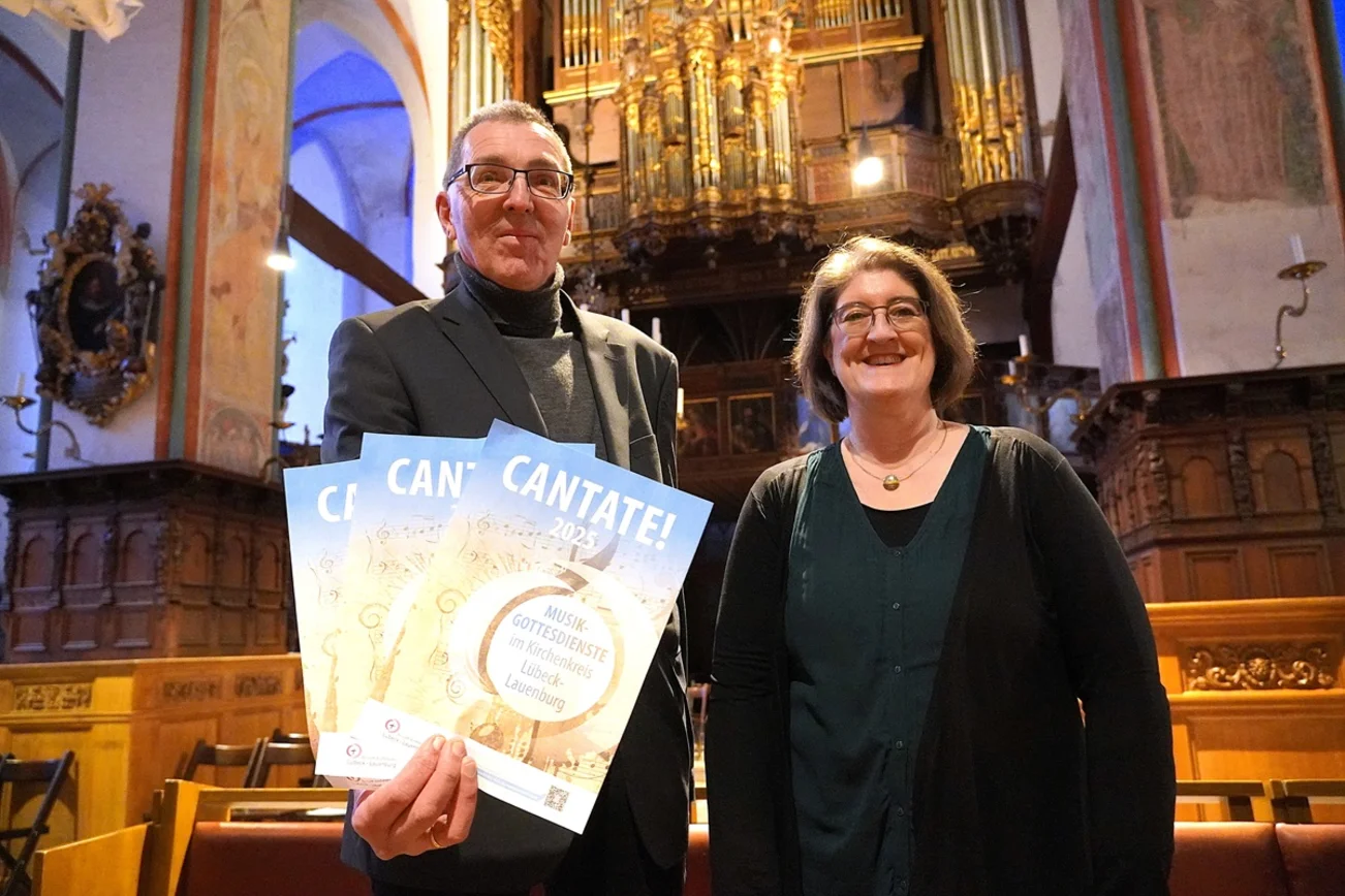 Kreiskantoren Gast und Bufo präsentieren Plakate zu "Cantate 2025" in St. Jakobi Lübeck