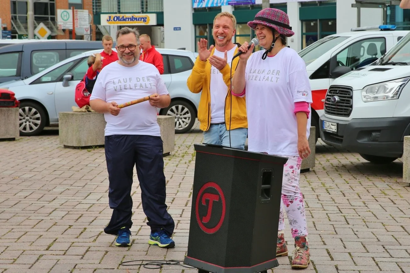 Drei fröhliche Menschen auf einem Platz.
