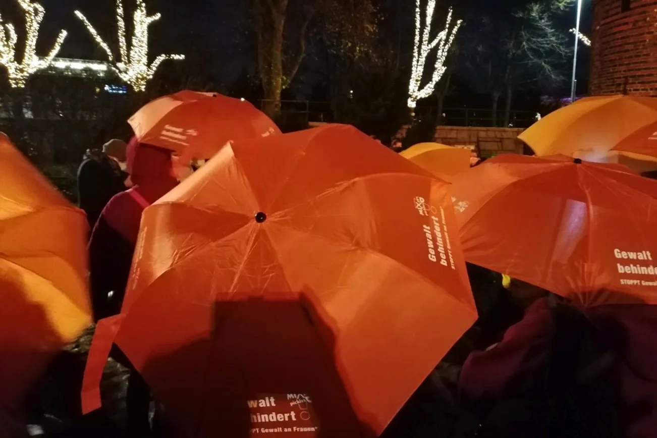 orange Schirme mit Aufschrift Gewalt behindert