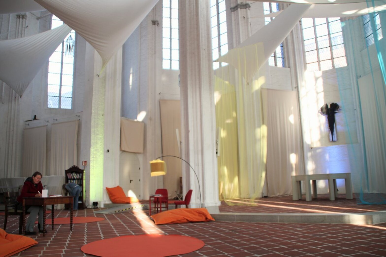 Blick in einen von der Sonne beleuchteten Kirchraum mit Sitzmöglichkeiten.