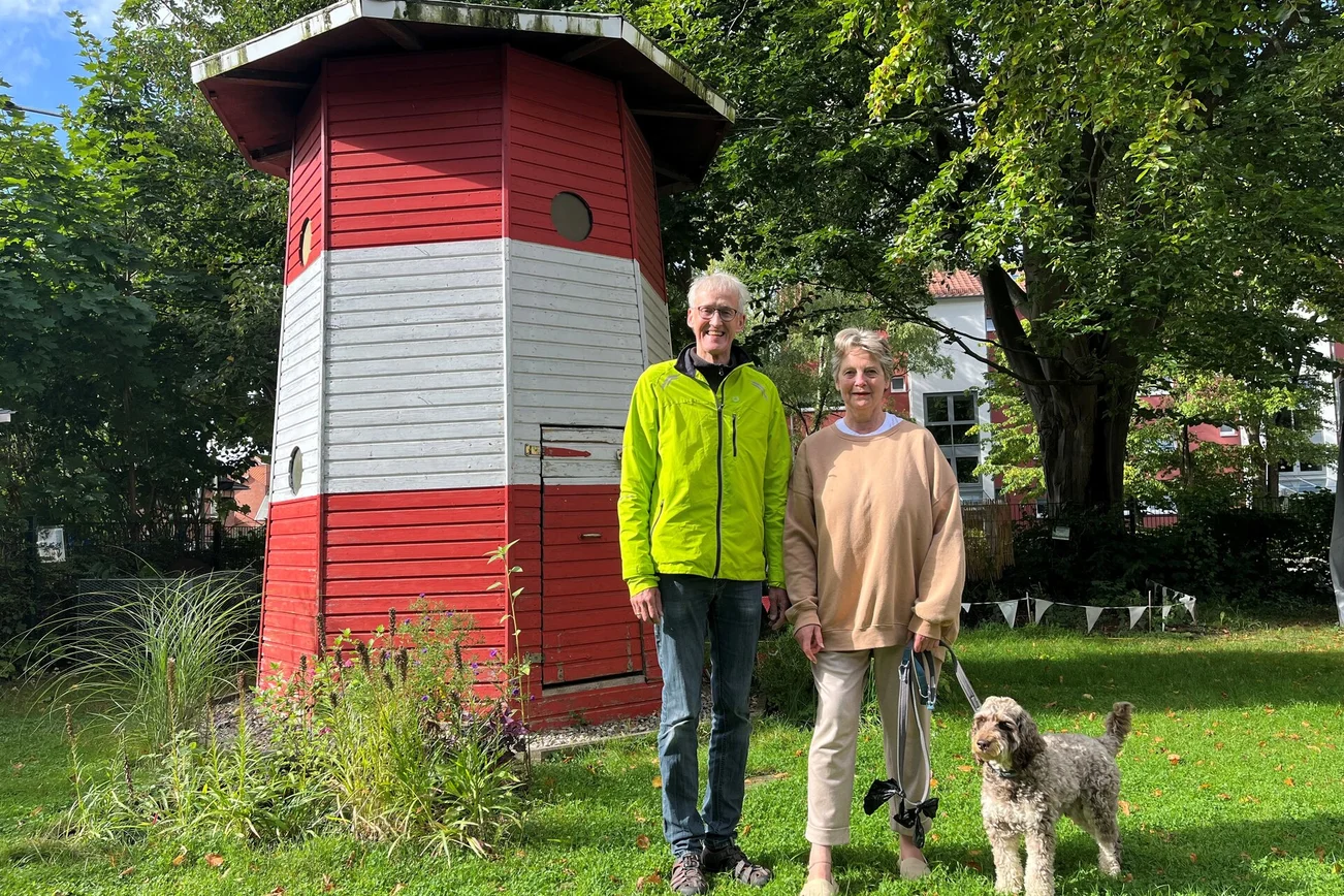 Ein Mann und eine Frau stehen lächelnd vor einem Leuchtturm.