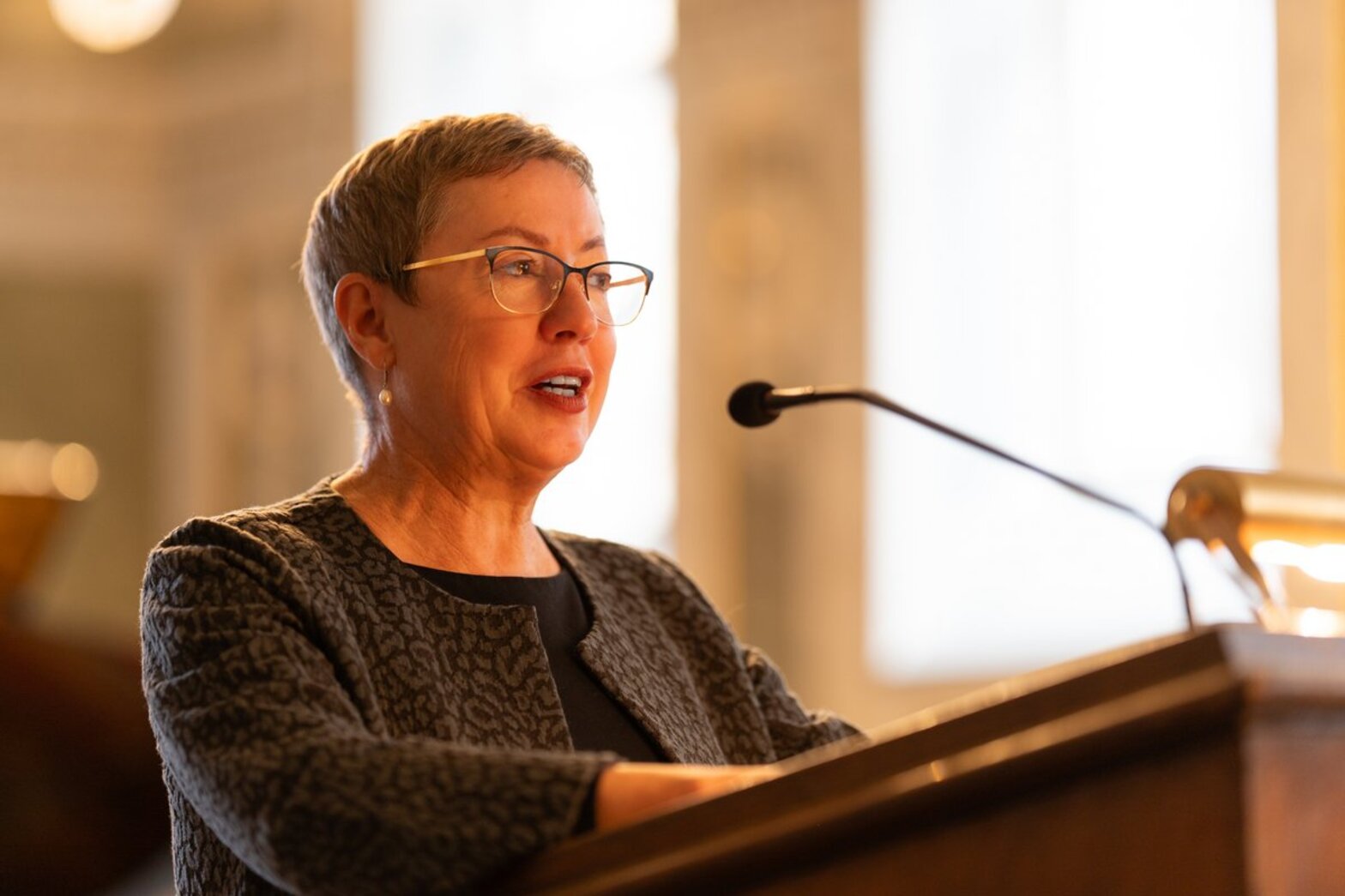 Eine Frau steht hinter einem Rednerpult mit Mikrofon.