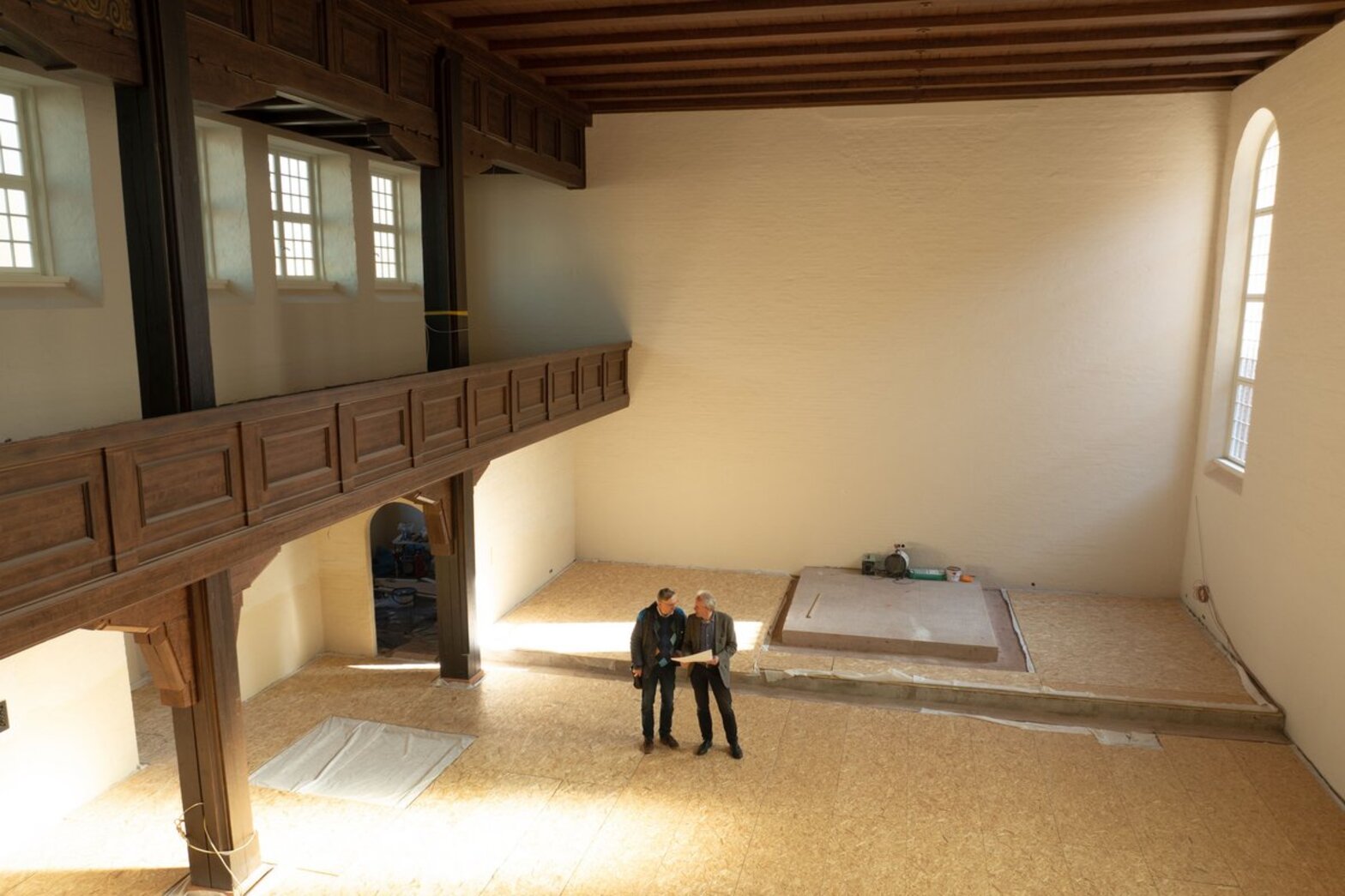 Zwei Männer stehen in einem leeren Kirchenraum. in den die Sonne scheint.
