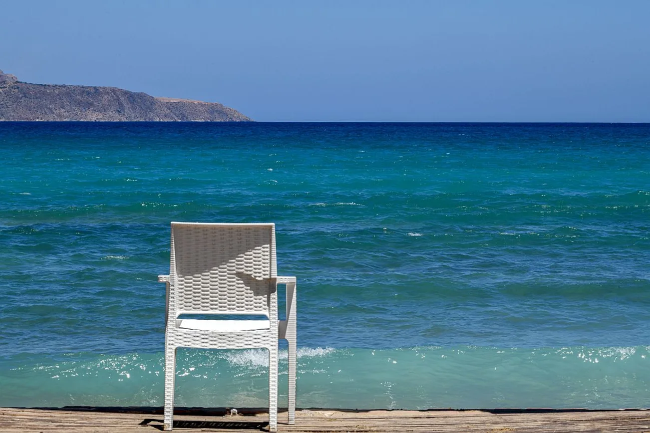 Weißer Stuhl am Strand mit Blick auf das blaue Meer