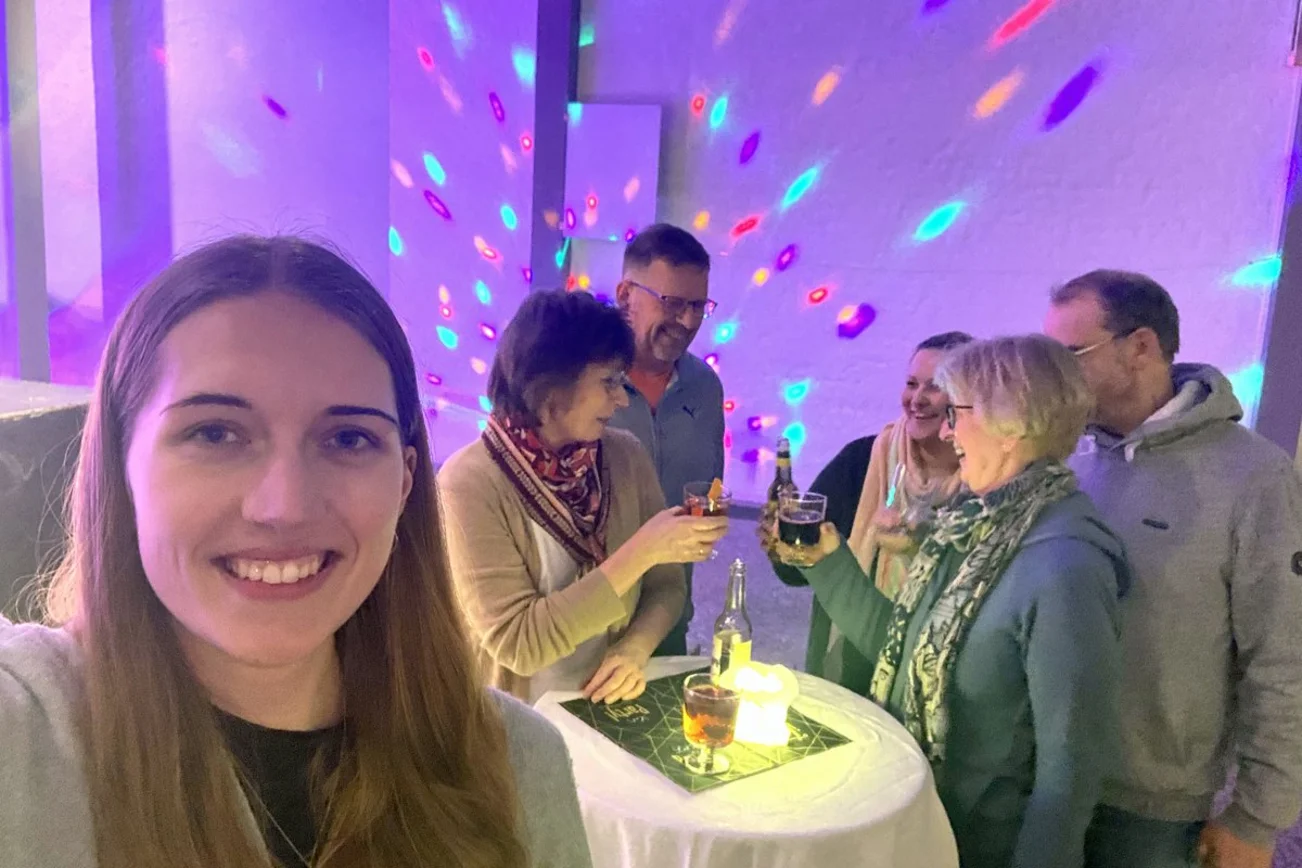 Eine junge Frau im Vordergrund mit mehreren Menschen in einem Partyraum.