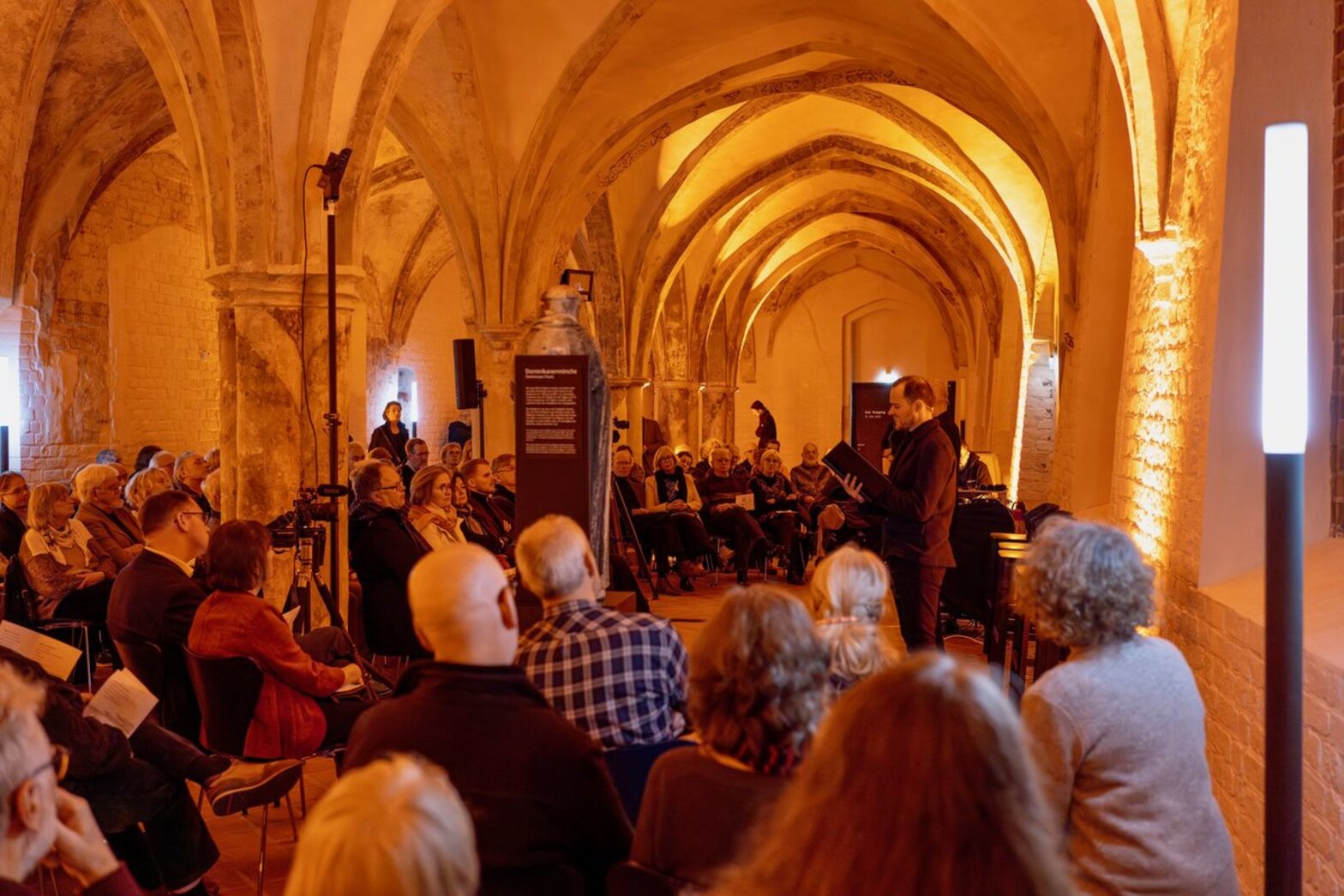 Blick in einen erleuchteten räum, in dem Menschen sitzen. 