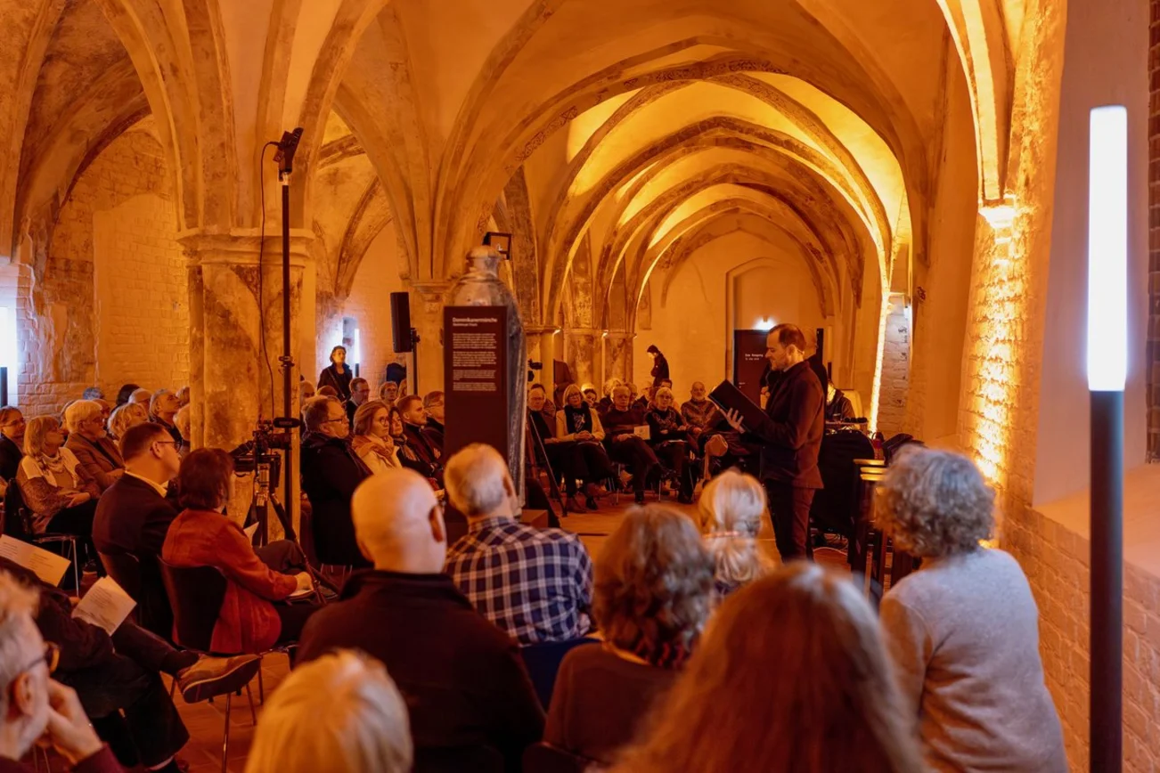 Blick in einen erleuchteten räum, in dem Menschen sitzen. 