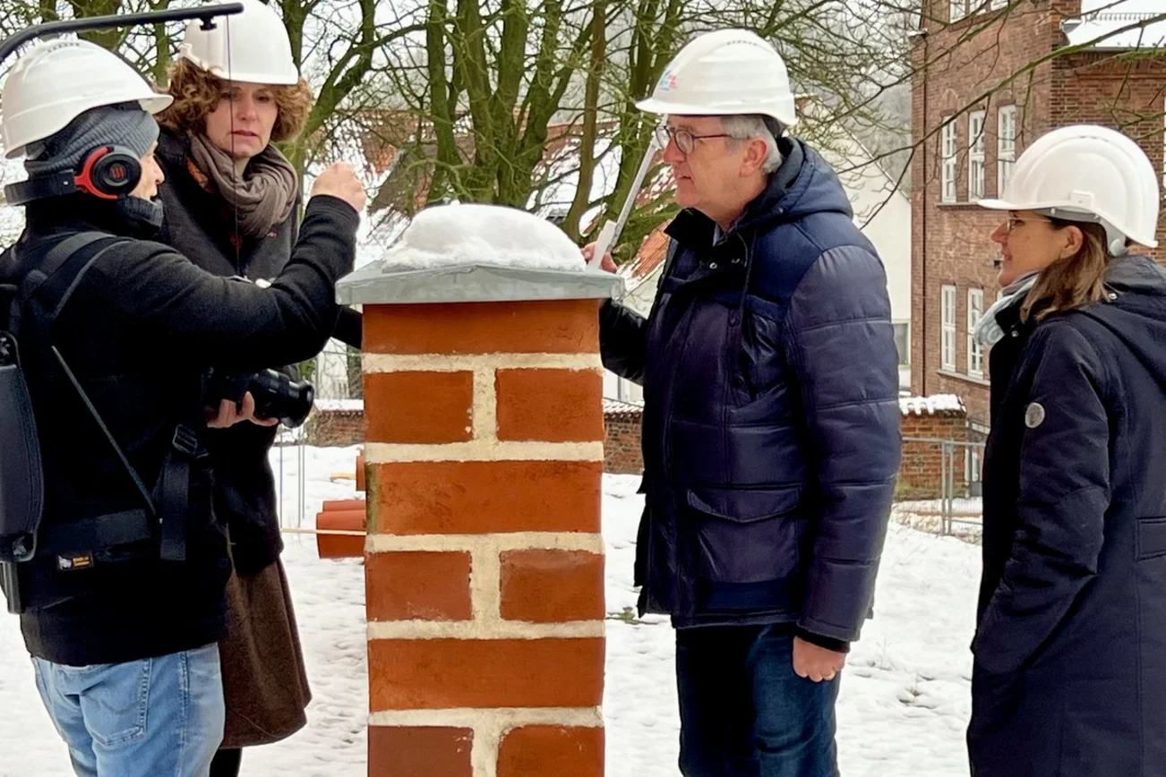 Menschen stehen an einer Mauer im Schnee