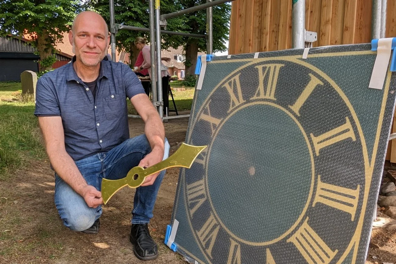 Ein Mann steht neben einer Turmuhr